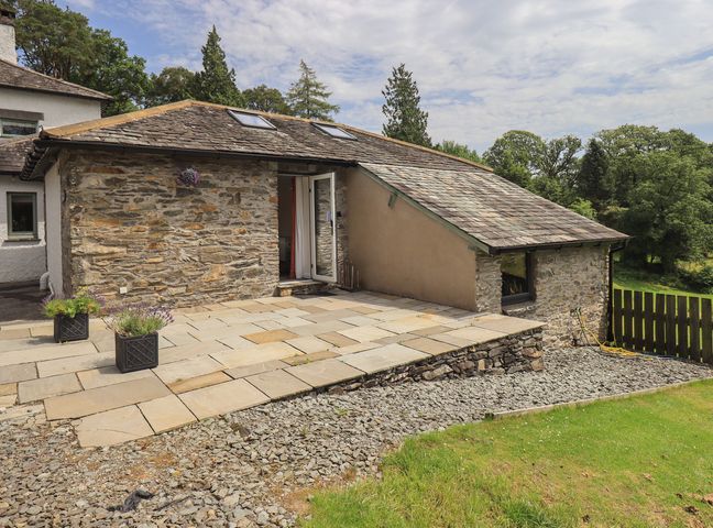 An outdoor area with a stone wall and patio at Acorn in Bowness-on-Windermere