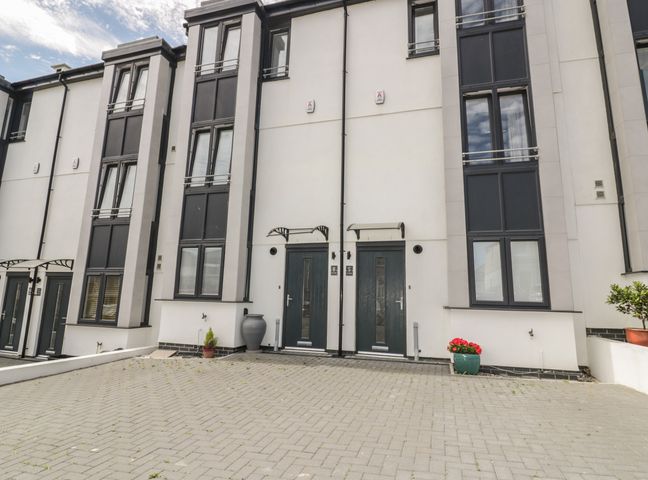The front exterior of a modern townhouse with two dark doors numbered 5 and 6 and large windows at 5 Ocean Heights in Newquay
