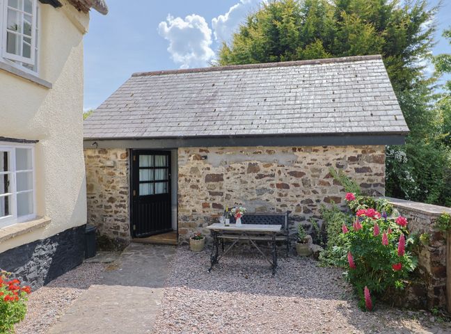 An outdoor seating area with a table and flowers at The Old Workshop Knowstone