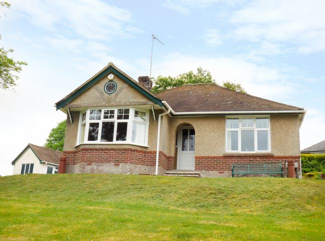 A single story house with a bay window and a front door surrounded by grass at Goodrest in Verwood