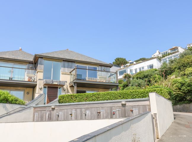 A building with a balcony and multiple numbered wooden storage units below at Rock Pool in Downderry