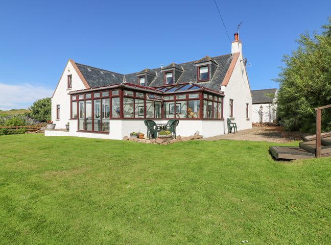 A house with a glass conservatory on a lawn with outdoor chairs at Old Cooperage Cruden Bay near Peterhead