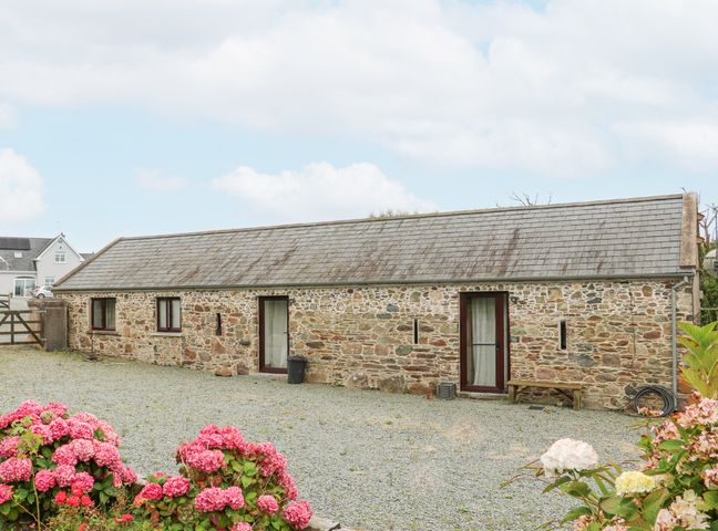 A stone building with two doors and three windows surrounded by gravel and flowers at Swallow's Nest in Tacumshane County Wexford