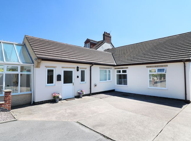 A white single-story house with a tiled roof and a concrete driveway at Cherry Fields in Bolsover