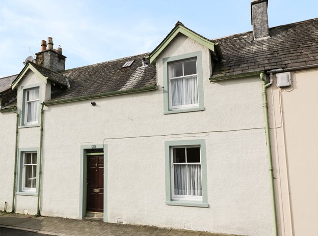 The exterior of a two story house with a door and windows with curtains at 27-29 St Marys Place Kirkcudbright