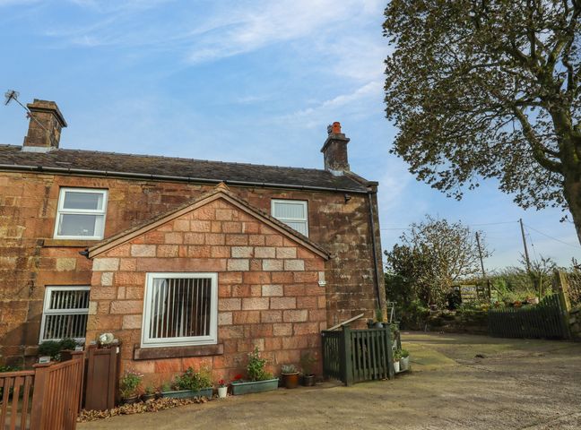 A stone house with two chimneys and windows surrounded by plants and trees at The Granary in Biddulph