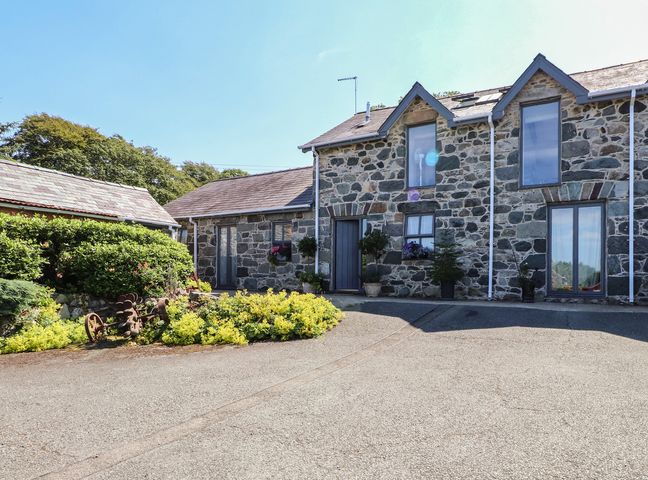 An exterior view of a stone house with plants at Wern Olau Cottage in Groeslon near Caernarfon