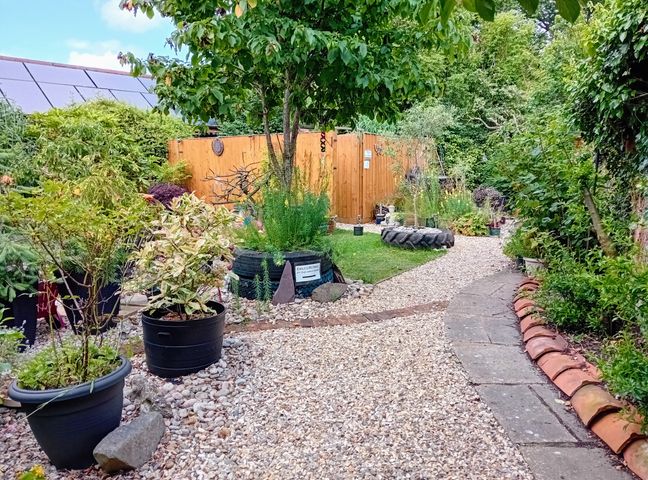 A garden with potted plants and gravel paths at Emilys Retreat at the Great Barn in Great Dunham Litcham