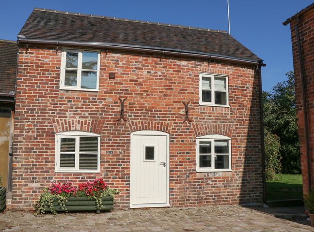 A brick house with a white door and four windows with flower boxes outside at Hollys Barn in Fulford