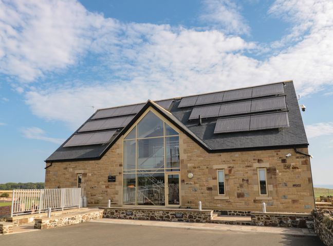 A stone building with solar panels on the roof and a large glass entrance at Newton View in Embleton