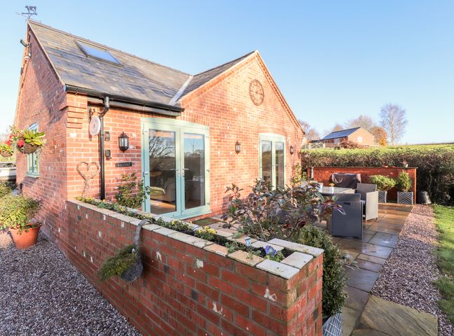 An outdoor patio area with seating and brick walls at Well View Cottage in Chester