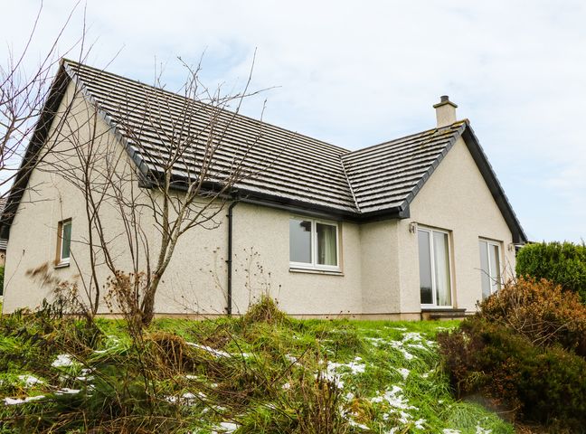 A house with a tiled roof and beige walls surrounded by grass and bushes at Glaven in Bonar Bridge