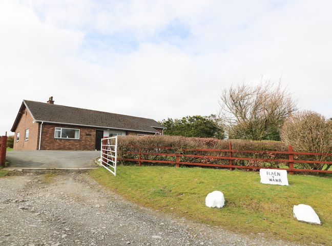 A single story brick house with a sloped roof near a gravel driveway and a gate at Blaenywawr Annexe in Lampeter