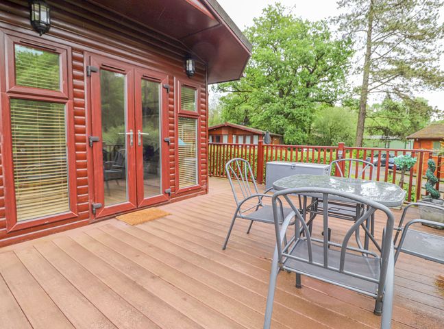 A wooden deck with metal chairs and a table outside a cabin at 10 Thirlmere White Cross Bay near Troutbeck Bridge