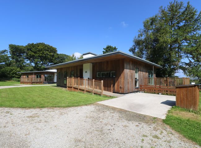 Two wooden houses with decks on a grassy area surrounded by trees at Birch in Truro