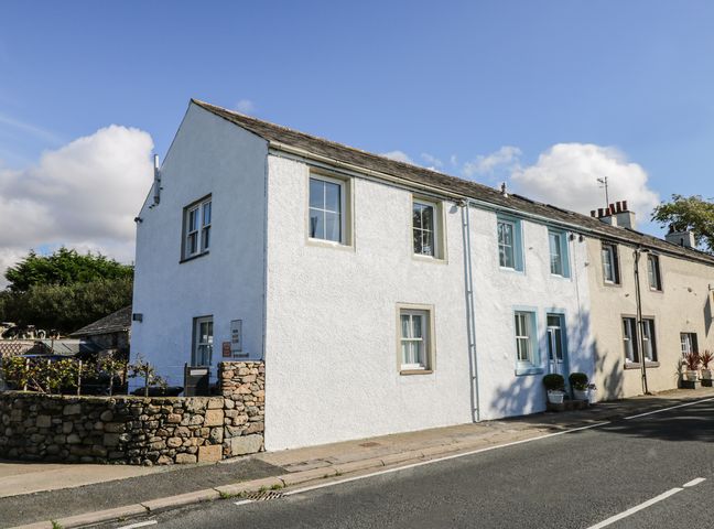 A row of terraced houses along a street with stone walls and potted plants at 1 Park Nook Close in Waberthwaite