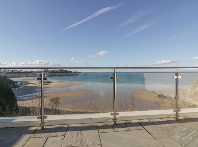 A glass balcony overlooking a sandy beach and ocean at Buena Vista in Newquay