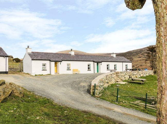 A white single-story cottage with chimneys and a curved gravel driveway in a rural area at Pat Whites Cottage in Rostrevor