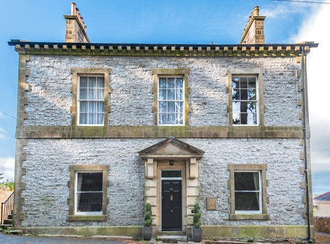 A stone two-story house with six windows and a black front door at Magistrates Chambers in Ingleton