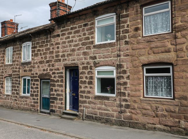 A street view of stone brick houses with windows and doors including a blue door at The Hill in Cromford