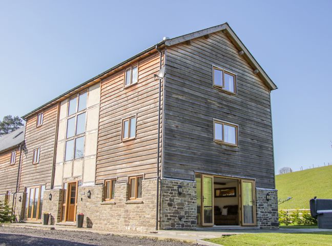 An exterior view of a three-story building with wood and stone facade at The Stables in Knighton