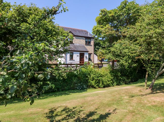 A stone and white house surrounded by trees and a grassy area at Tranquility in Falmouth