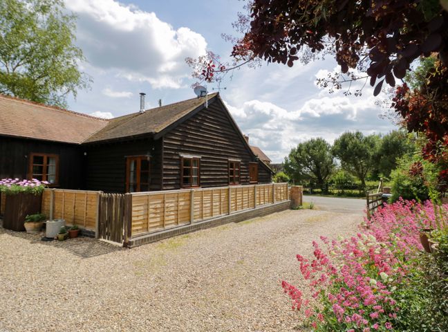 A house with a fence and flowers in the garden at Robbie's Barn, Fulready near Stratford-upon-Avon