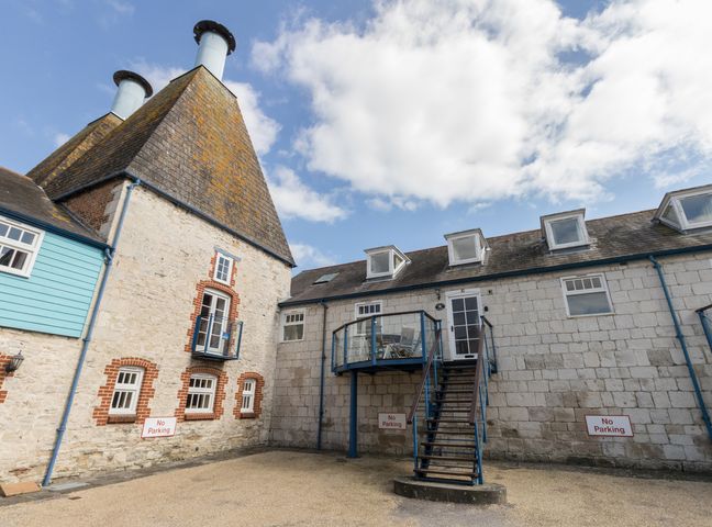 An exterior courtyard with stone buildings a staircase and no parking signs at George's House in Brewers Quay Harbour