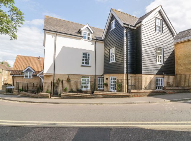 A street view of a residential building with white and black exterior walls and multiple windows at The Hoist in Ely