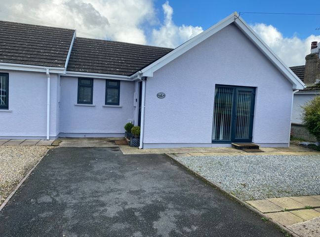 The exterior of a single-story house with a driveway and gravel area at Cranford Cottage Pembroke