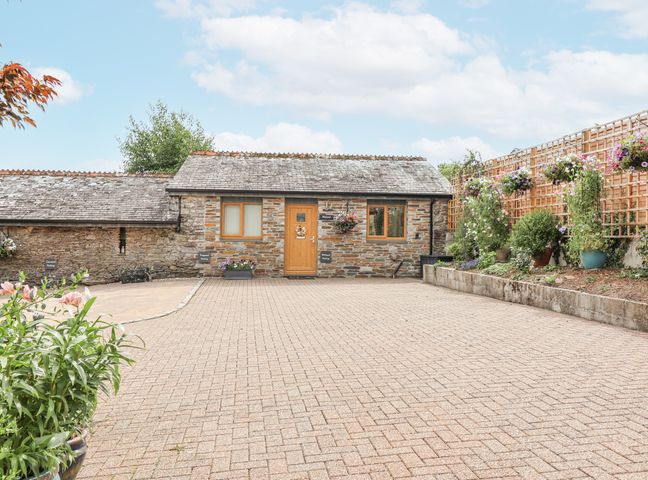 An outdoor area with a stone building and flower pots at Whitsand in Tideford