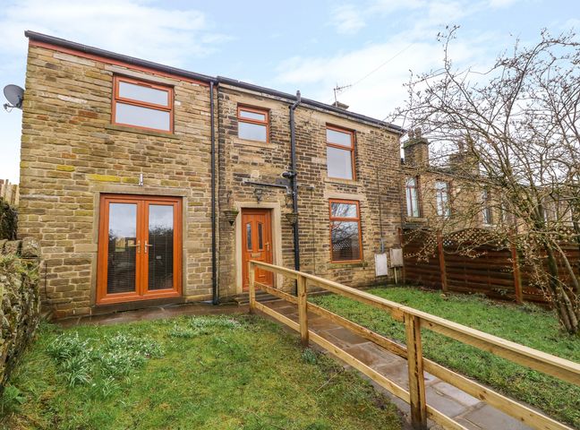 A stone house with wooden framed windows and doors and a ramp leading to the entrance at Moscow Mews in Thornton