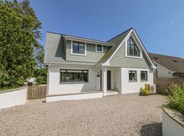 A two-story house with a gravel driveway and green siding at Garden House in Gorran Haven