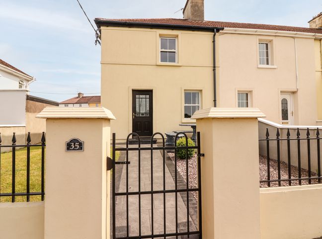 The exterior of a semi detached house with a black front door a paved pathway and a metal gate at 35 Laune View in Killorglin near Killarney