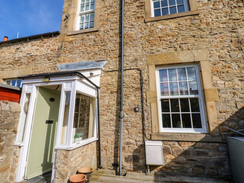 An outdoor view showing an entrance and stone wall at Old Workhouse Cottage in Stanhope