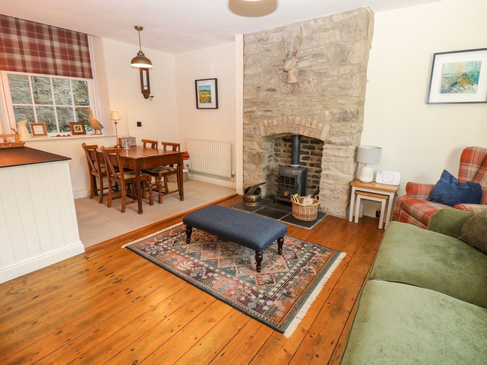 A living room with a fireplace and dining area at Old Workhouse Cottage in Stanhope