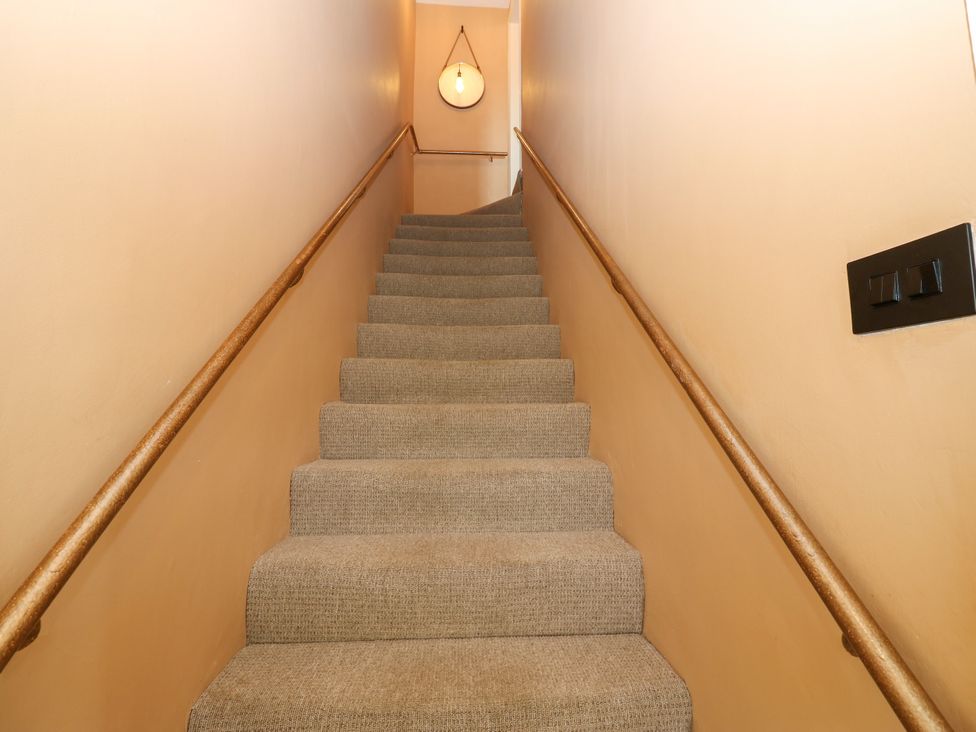 A staircase with beige carpet and a handrail at Old Workhouse Cottage in Stanhope
