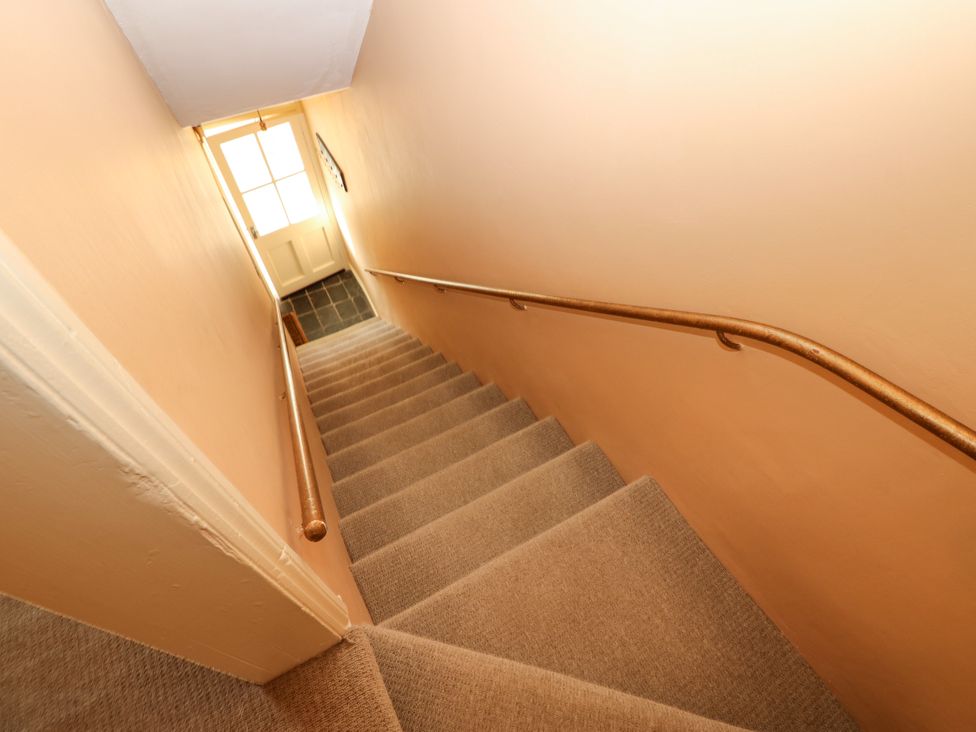 A stairway with a handrail and door at Old Workhouse Cottage in Stanhope
