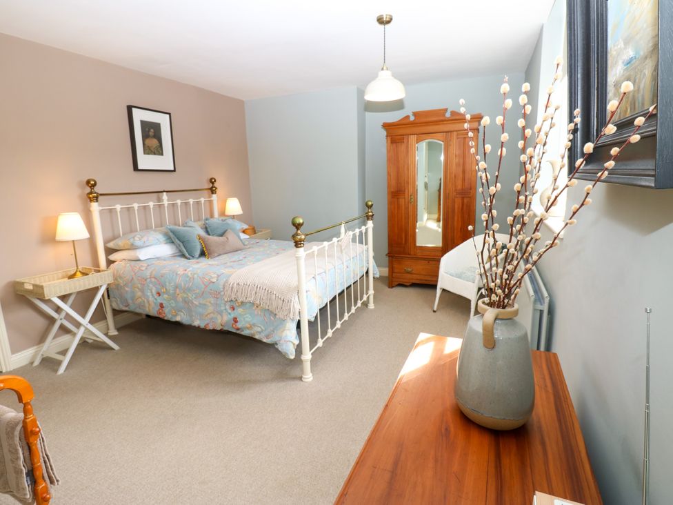 A bedroom with a bed and a wardrobe at Old Workhouse Cottage in Stanhope