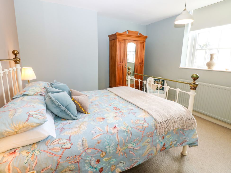 A bedroom with a bed, wardrobe, and lamp at Old Workhouse Cottage in Stanhope