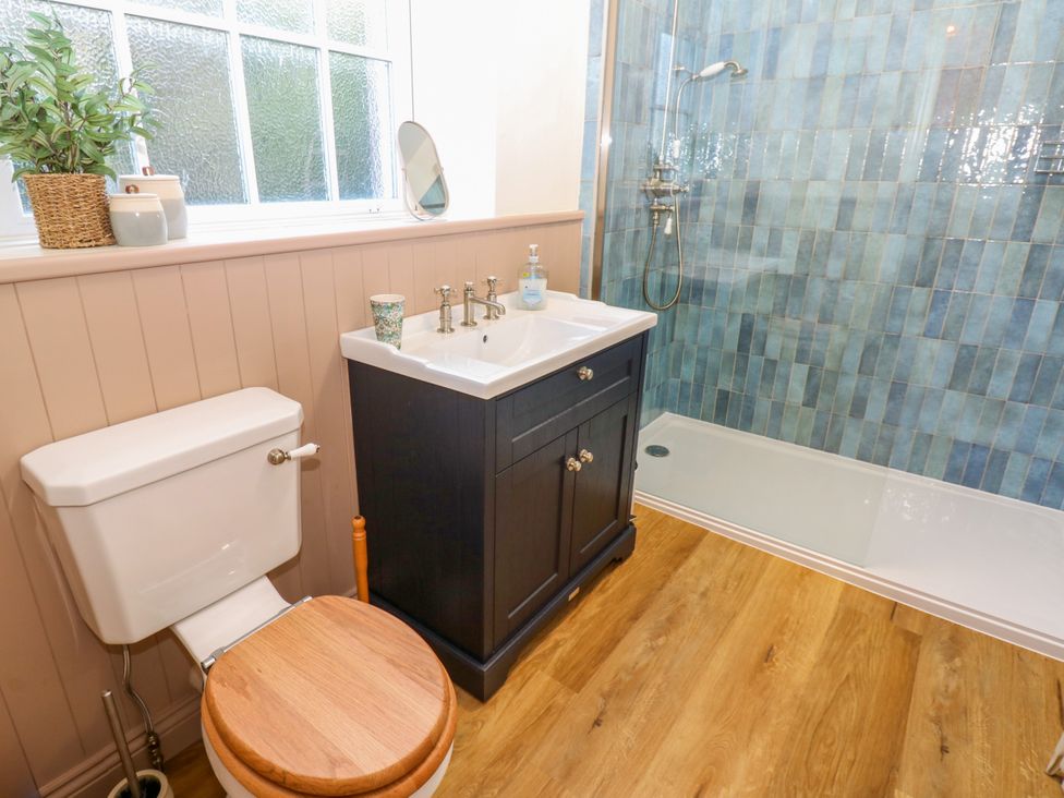 A bathroom with a toilet, sink, and shower at Old Workhouse Cottage in Stanhope