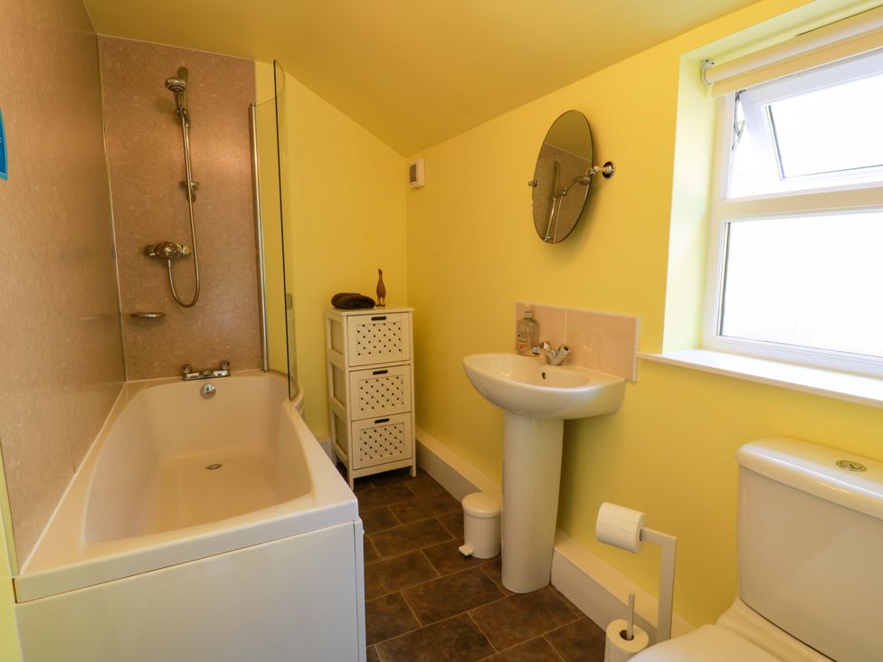 A bathroom with a bathtub, shower, sink, and toilet at Cairnhill in Girvan