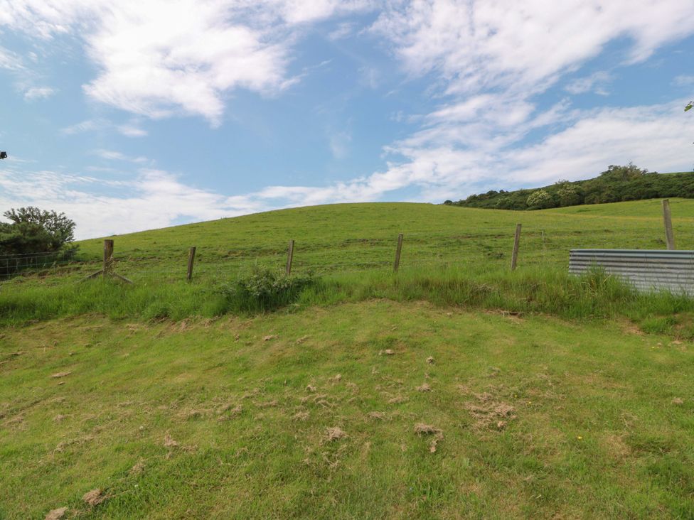 A green hill with a fence and blue sky at Cairnhill in Girvan