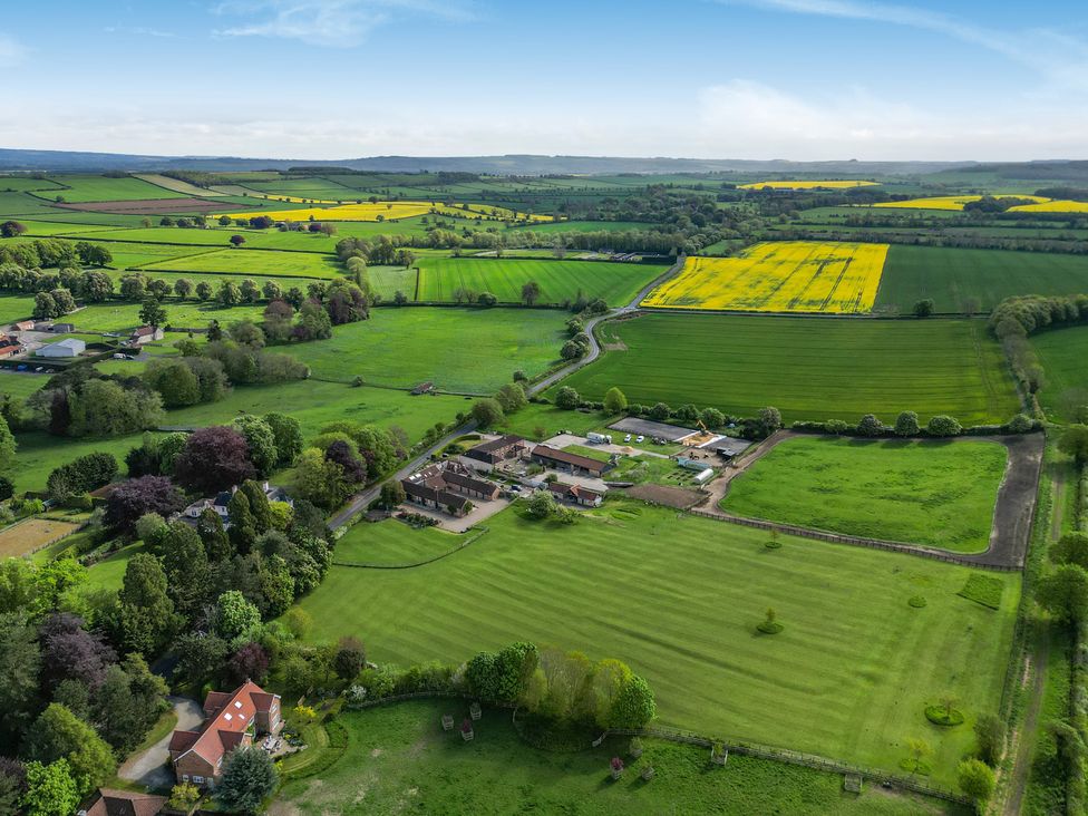 An aerial view of a farm surrounded by fields and trees at Sykes Lodge Malton