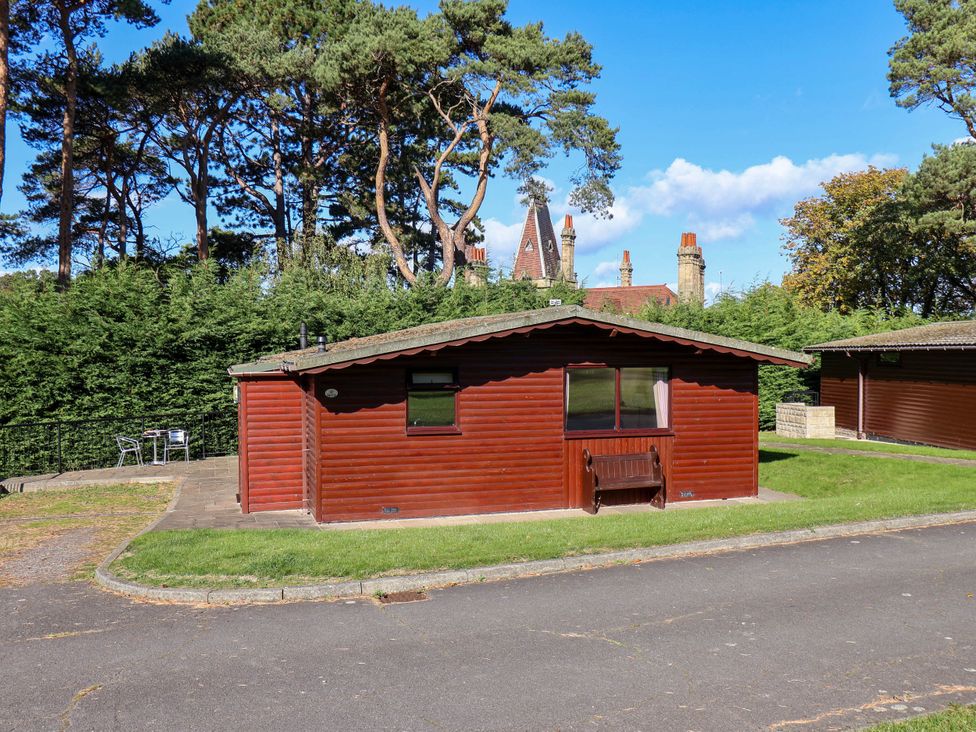A log cabin with windows and outdoor seating at Orchid Lodge in Saltburn-by-the-Sea