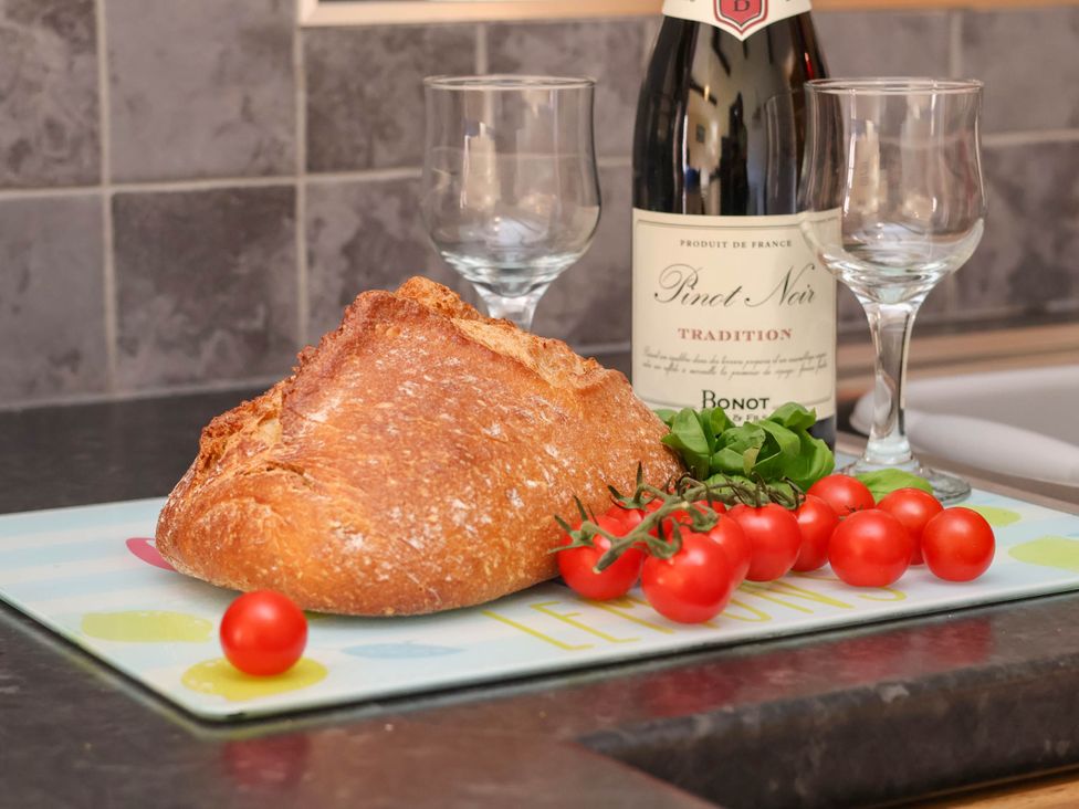 A kitchen counter with bread, wine, and tomatoes at Orchid Lodge Saltburn-by-the-Sea