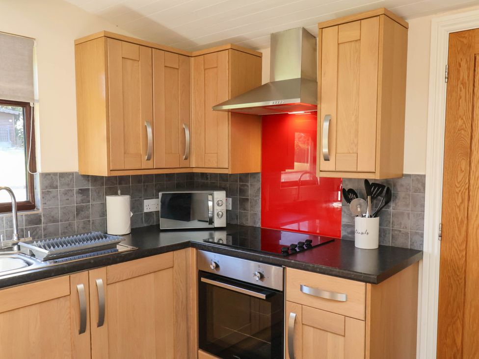 A kitchen with wooden cupboards and appliances at Orchid Lodge in Saltburn-by-the-Sea