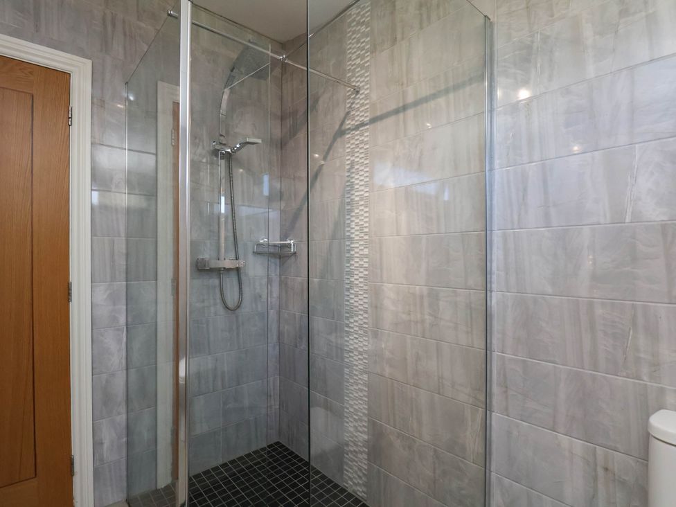 A shower with glass door and tiles at Orchid Lodge Saltburn-by-the-Sea