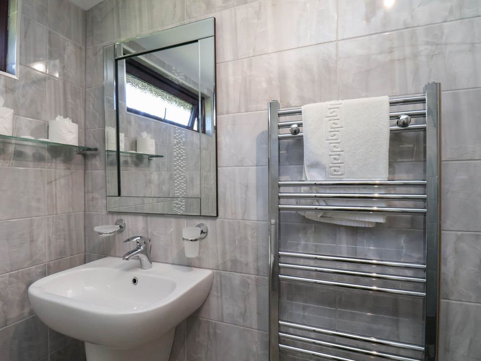 A bathroom with a sink, mirror, and towel rail at Orchid Lodge in Saltburn-by-the-Sea