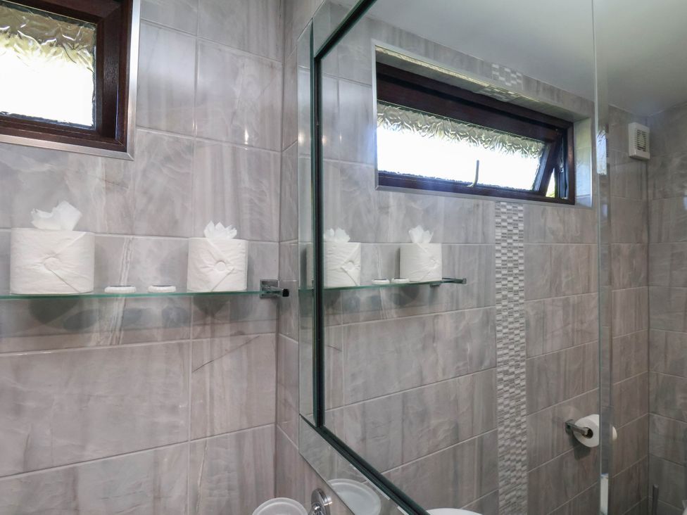 A bathroom with a mirror and toilet paper on a shelf at Orchid Lodge in Saltburn-by-the-Sea